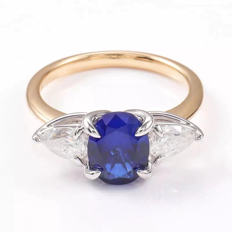 Two Carat Oval Cut Lab Created Blue Sapphire and Pear Cut Moissanite Engagement Ring in 14 Karat Gold - Boutique Pavè