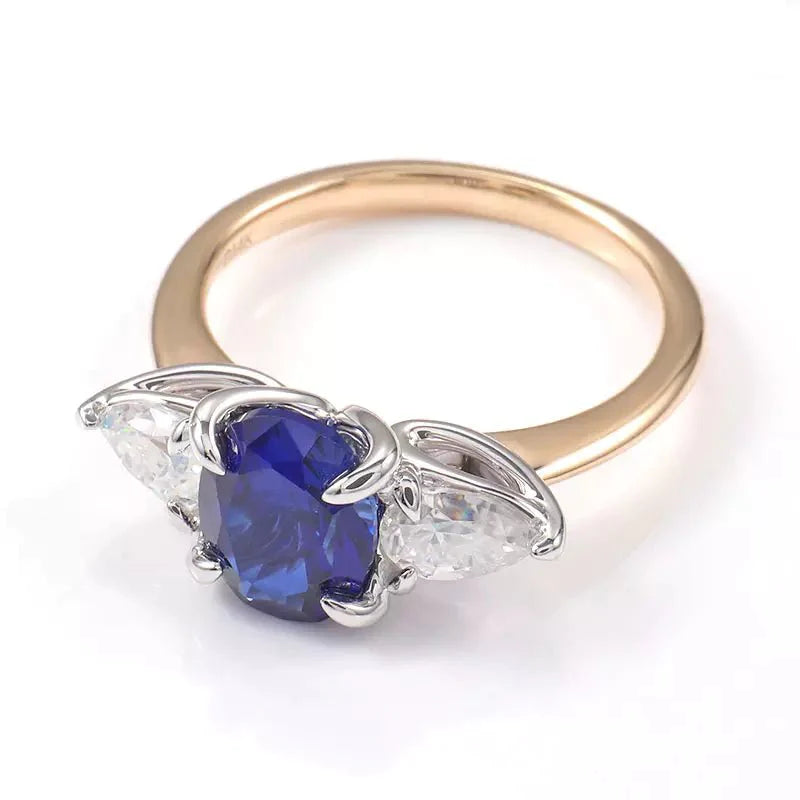 Two Carat Oval Cut Lab Created Blue Sapphire and Pear Cut Moissanite Engagement Ring in 14 Karat Gold - Boutique Pavè